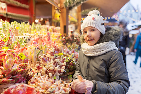 假期,童人的快乐的小女孩与棒棒糖诞市场糖果店晚上诞节市场糖果店里棒棒糖的女孩图片
