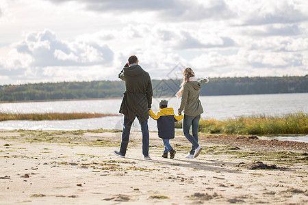 家庭休闲人的快乐的母亲父亲小儿子沿着秋天的海滩散步幸福的家庭沿着秋天的海滩散步图片
