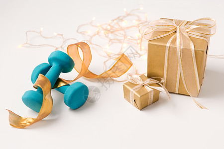 寒假,新诞节的礼品盒包装成金色的纸蓝色的哑铃白色的背景诞礼品盒白色哑铃图片
