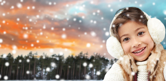 诞节,季节人的快乐的小女孩戴着耳罩冬天的森林背景冬天森林里戴着耳罩的快乐小女孩图片