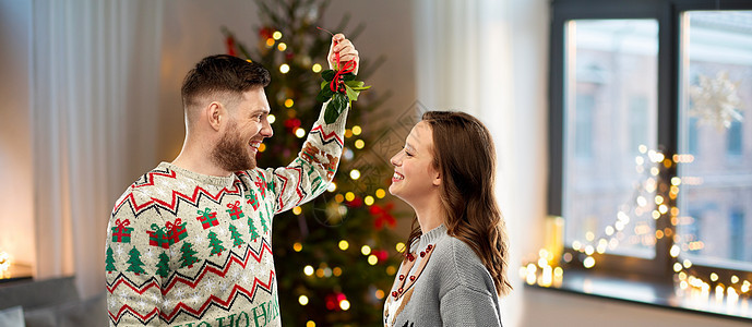 诞节,人们节日传统的幸福的夫妇毛衣与槲寄生家里的背景诞快乐的夫妇槲寄生家里图片