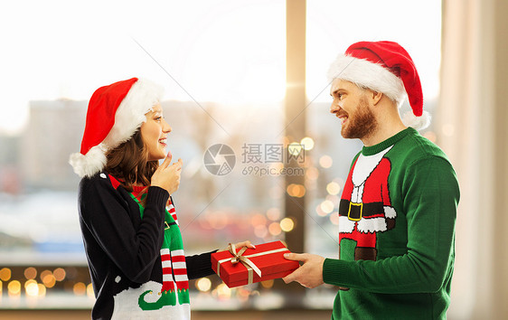 人们节日的幸福的夫妇戴着诞帽,毛衣派上家庭房间背景诞毛衣礼品盒的幸福夫妇图片