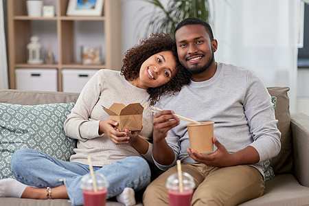外卖食品,饮料人们的快乐的非裔美国人夫妇家用筷子吃炒锅幸福的夫妇带着外卖食品饮料家图片