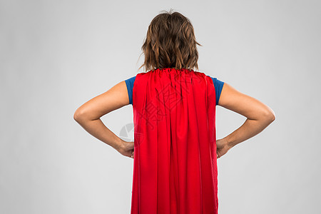 女人的力量人的背的轻女人红色超级英雄斗篷灰色背景红色超级英雄斗篷的轻女人的背景图片