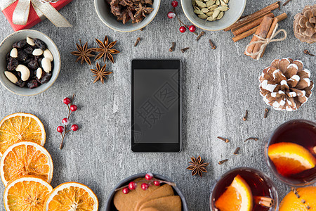 诞节,寒假技术智能手机,热覆盖葡萄酒,干橙色切片芳香香料灰色背景智能手机,热覆盖葡萄酒诞香料图片