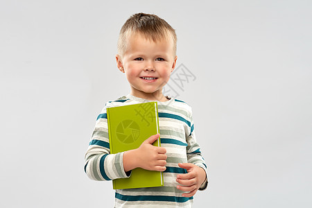 阅读教育童微笑的小男孩灰色背景下着书的肖像微笑男孩着书的肖像图片