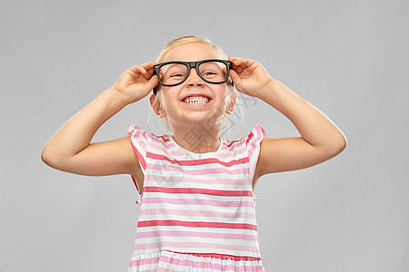 教育,学校视觉微笑可爱的小女孩戴着黑色眼镜,灰色背景微笑可爱的小女孩戴着黑色眼镜图片