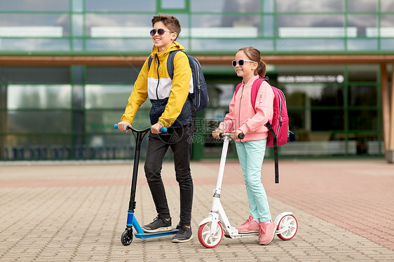 教育,童人的快乐的学校孩子与背包滑板车户外带背包滑板车的快乐学校孩子图片