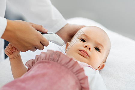 医学,医疗儿科女儿科医生与数字红外温度计测量女婴病人的耳温诊所医院带温度计的医生测量婴儿的温度背景图片