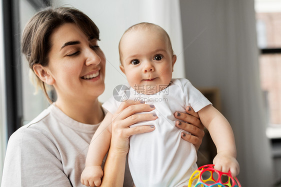 家庭孩子父母的快乐的微笑轻母亲抱着灰色背景的小女儿快乐的轻母亲抱着小女儿图片