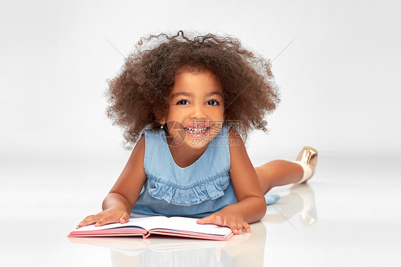童,学校教育快乐微笑的非裔美国女孩阅读书籍灰色背景微笑的非裔美国女孩看书图片
