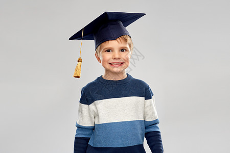 学校,教育学小男孩学士帽迫击炮戴着学士帽灰泥板的小男孩图片