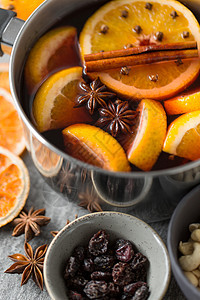 诞节季节饮料锅与热覆盖葡萄酒,橙色切片芳香香料灰色背景锅里热覆盖的葡萄酒橘子片香料图片