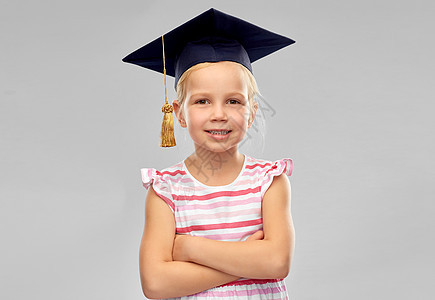 学校,教育学快乐的小女孩戴着学士帽灰背景的灰泥板戴着学士帽灰泥板的快乐女孩图片