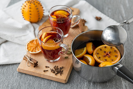 诞节季节饮料锅与热覆盖葡萄酒,橙色片,芳香香料瓢灰色背景锅里热覆盖的葡萄酒橘子片香料图片