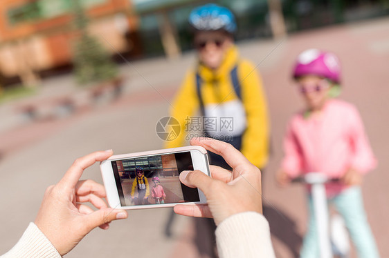 教育,童人的近距离的手,拍摄学校的孩子戴着头盔,背包滑板车,智能手机户外用智能手机拍照学校孩子的手图片