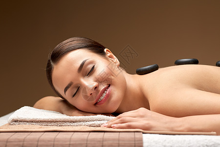 微笑的女人水疗中心热石按摩背景图片