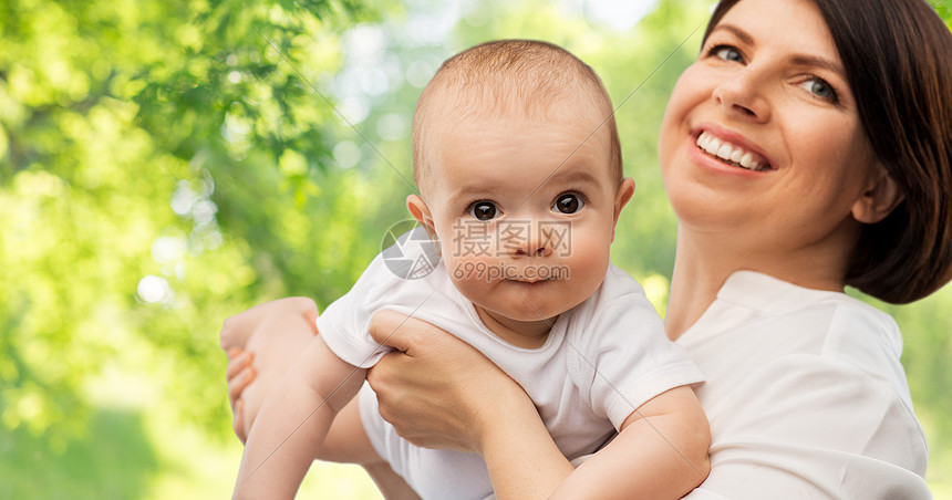 家庭,孩子父母的快乐的微笑中母亲抱着小宝贝女儿绿色的自然背景快乐的中母亲小女儿图片