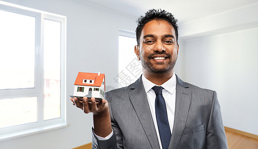房地产业务人的印度男子房地产经纪人与房屋模型空的新公寓房间背景印度男子房地产经纪人与房屋模型新家图片