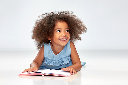 童,学校教育快乐微笑的非裔美国女孩阅读书籍灰色背景微笑的非裔美国女孩看书图片