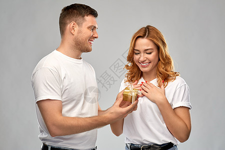 关系,假日情人节的幸福的夫妇穿着白色T恤与诞礼物灰色背景幸福的夫妇穿着白色T恤诞礼物图片