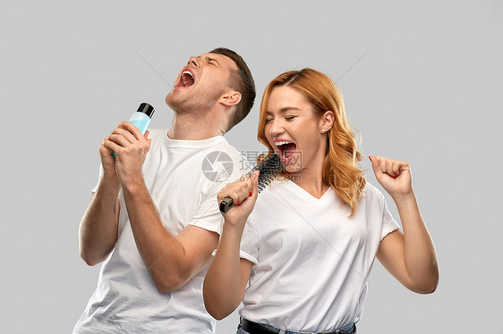 人际关系人的幸福的夫妇白色T恤夫妇唱歌的梳子洗剂瓶灰色背景快乐的夫妇唱歌给梳子乳液图片