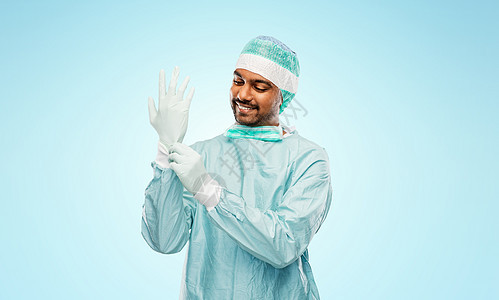 微笑的印度男医生穿着防护服戴手套图片