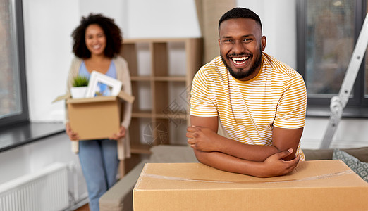移动,维修房地产快乐的非裔美国人夫妇新家的纸板箱里装东西幸福的夫妇带着箱子搬新家图片