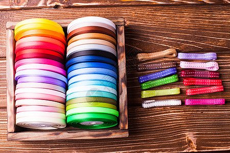 各种颜色的丝带筒子老式木箱木制桌子上五颜六色的丝带筒子图片