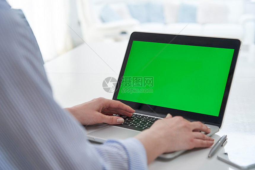办公室里用绿色屏幕笔记本电脑的女商人的肩膀上图片