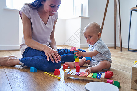 母亲与8个月大的婴儿儿子学玩彩色木块家里图片