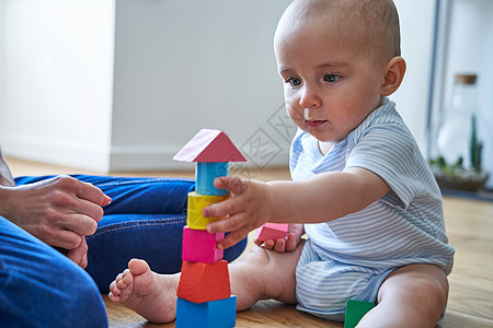 母亲与8个月大的婴儿儿子学玩彩色木块家里图片