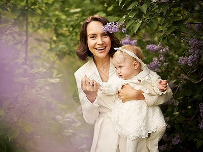 户外时尚肖像轻美丽的母亲小可爱的女儿开花公园丁香花春天的形象图片