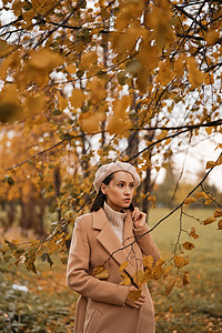 户外时尚照片,轻美丽的女士穿着米色外套,针毛衣贝雷帽包围秋叶温暖的秋天图片