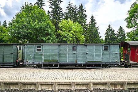 多云天气的背景下,火车车厢铁路上,车站绿树图片