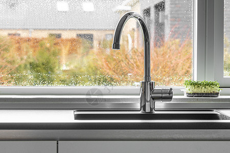 镀铬水龙头由厨房水槽与潮湿的窗户背景背景图片