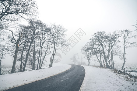 公路弯曲的道路雾蒙蒙的冬季风景与雪路边图片