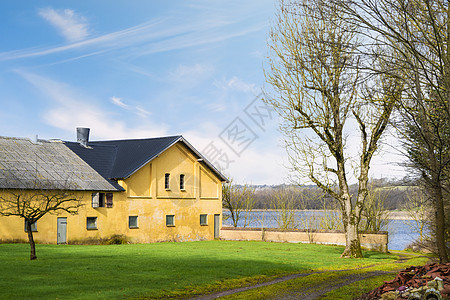 春天湖边的黄色农舍,院子里片绿色的草坪图片
