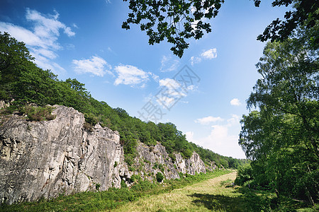 绿色的草地山谷里,悬崖夏天的蓝天下上升图片