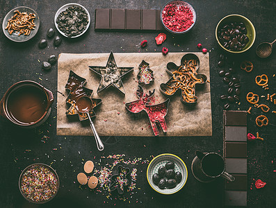 自制诞巧克力棒制作带各种浇头调味品的诞刀具融化的巧克力碗与勺子黑暗的乡村厨房桌子背景,顶部视图可食用的礼图片