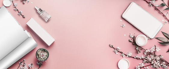 智能手机开放杂志模拟粘贴粉红色桌背景与化妆品开花枝,顶部视图美容博客女商业理念平躺框架横幅模板图片