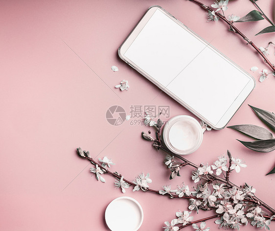 智能手机模拟粘贴粉红色桌背景与化妆品开花,顶部视图美容博客女商业理念图片
