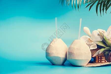新鲜的热带椰子鸡尾酒,喝吸管,棕榈叶花站蓝色的绿松石背景上夏季热带假期,旅游度假图片