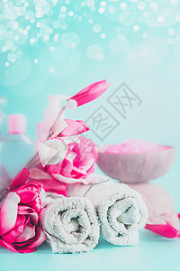 水疗毛巾与粉红色的花浅蓝色背景与Bokeh美丽的图片