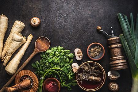 乡村食品背景与欧芹根蔬菜,草药,香料,韭菜香皮蘑菇黑暗的乡村餐桌上与厨房用具,顶部视图素食图片