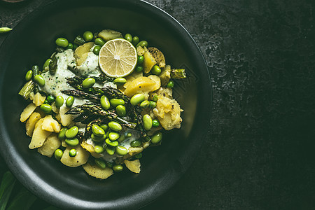 土豆绿色芦笋沙拉与芝麻大豆黑色碗,顶部视图与健康素食图片