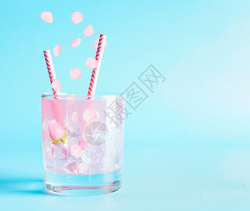 夏季饮料与玫瑰花瓣花点心饮料蓝色背景上的冰柠檬鸡尾酒图片
