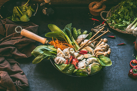 韩国火锅的准备炒锅与蔬菜饺子黑暗的乡村厨房桌子背景与配料,顶部视图图片