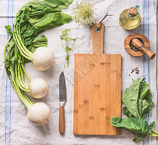 生幼萝卜与绿色轻厨房桌子上与空切割板刀,顶部视图健康素食清洁饮食烹饪理念图片