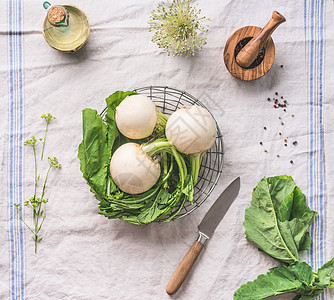 生幼萝卜与绿色轻厨房桌子上与刀,顶部视图健康的素食饮食烹饪理念图片
